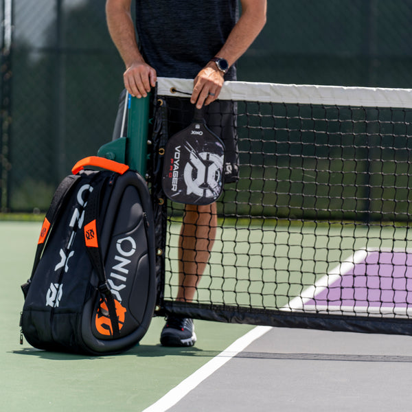 pickleball player with pickleball backback and pickleball paddle next to pickleball net